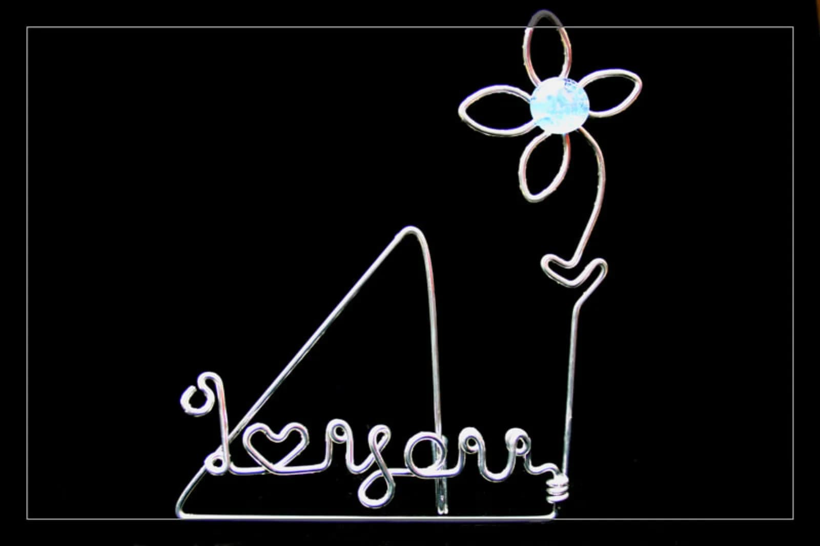 Wire art piece bending a guest name into a heart shape with a wire flower, a keepsake from the wire art station