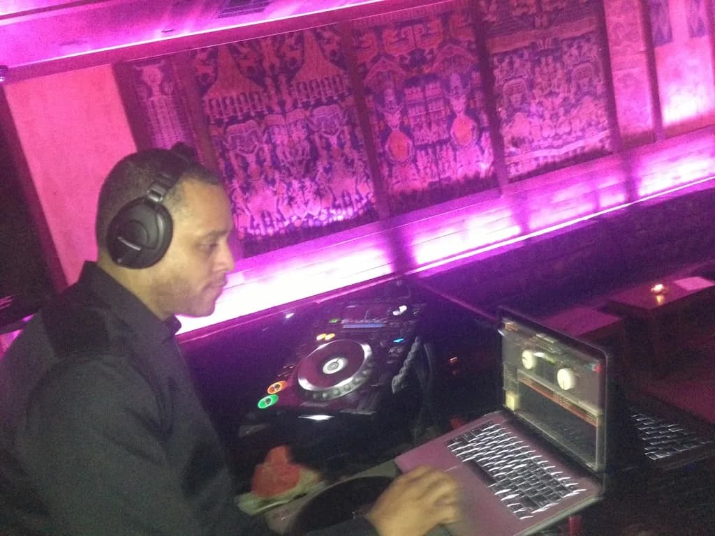 DJ David Raimer at the decks against an ornate purple-lit backdrop at a New York club event