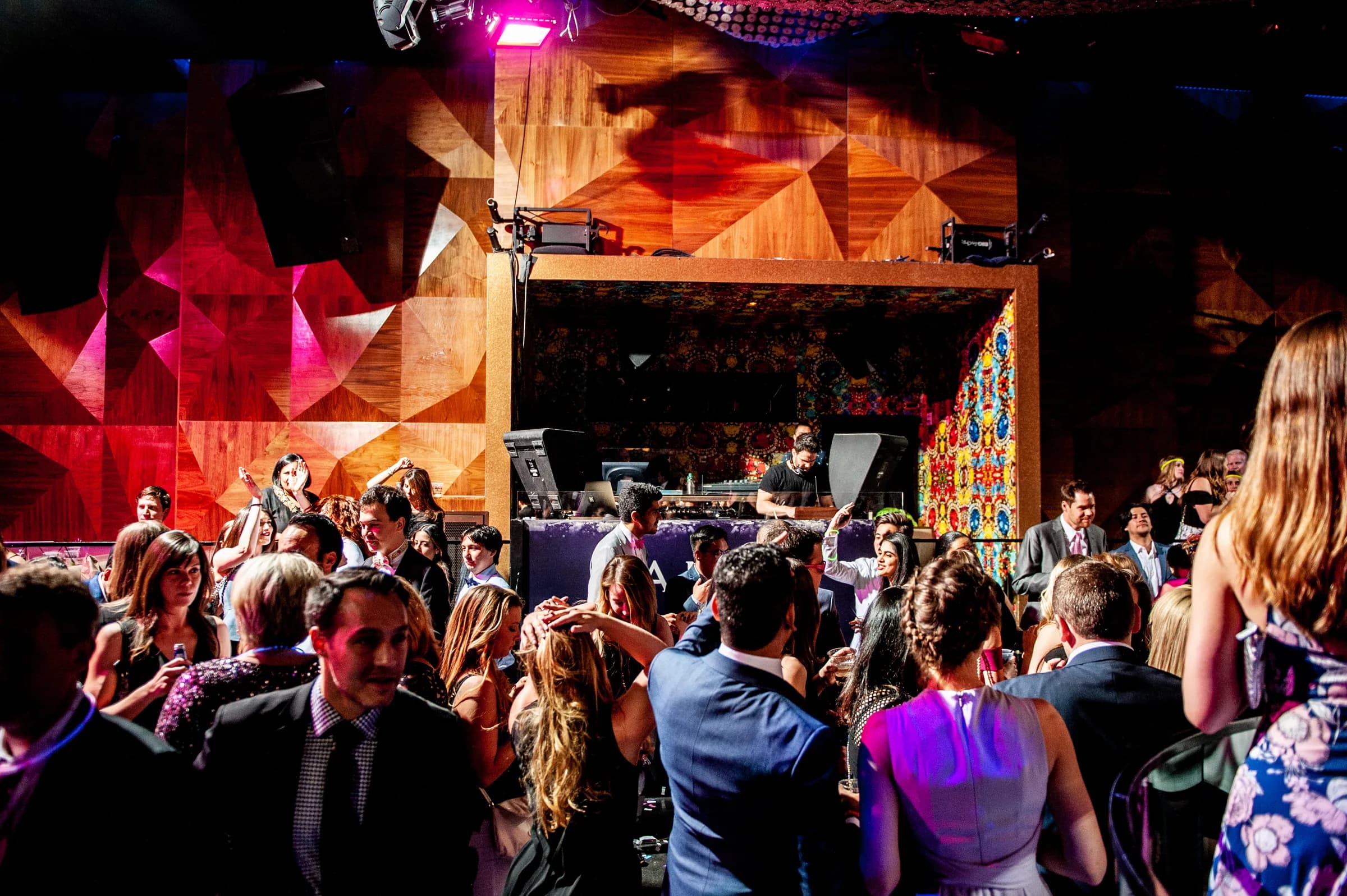 Packed club crowd under deep red stage lighting at one of Gabriel's events, atmospheric backdrop