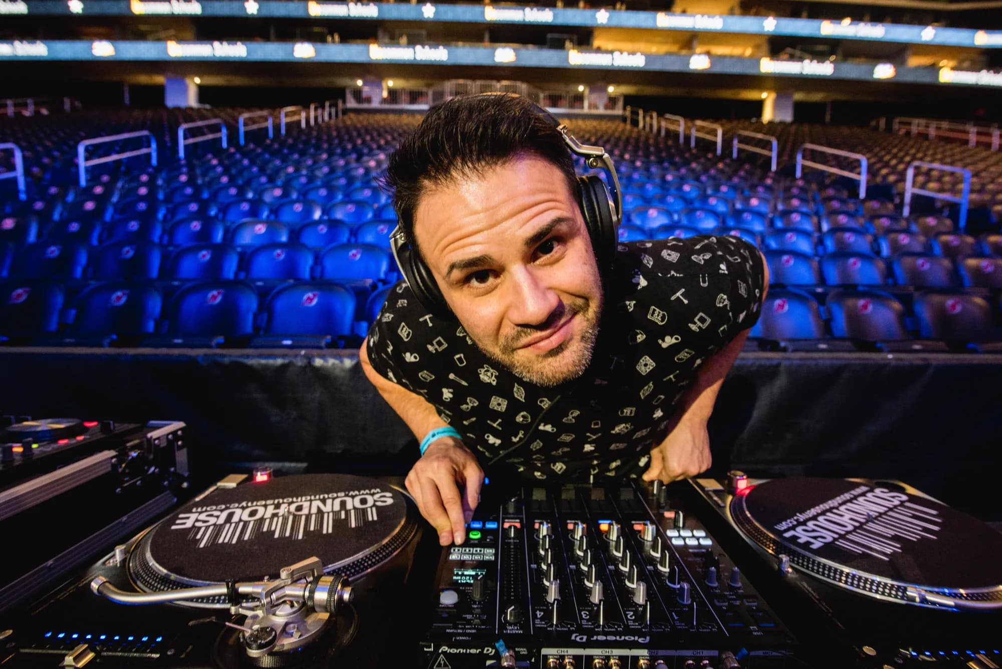 Gabriel at the decks leaning over the mixer with a packed arena behind him at a large-scale event