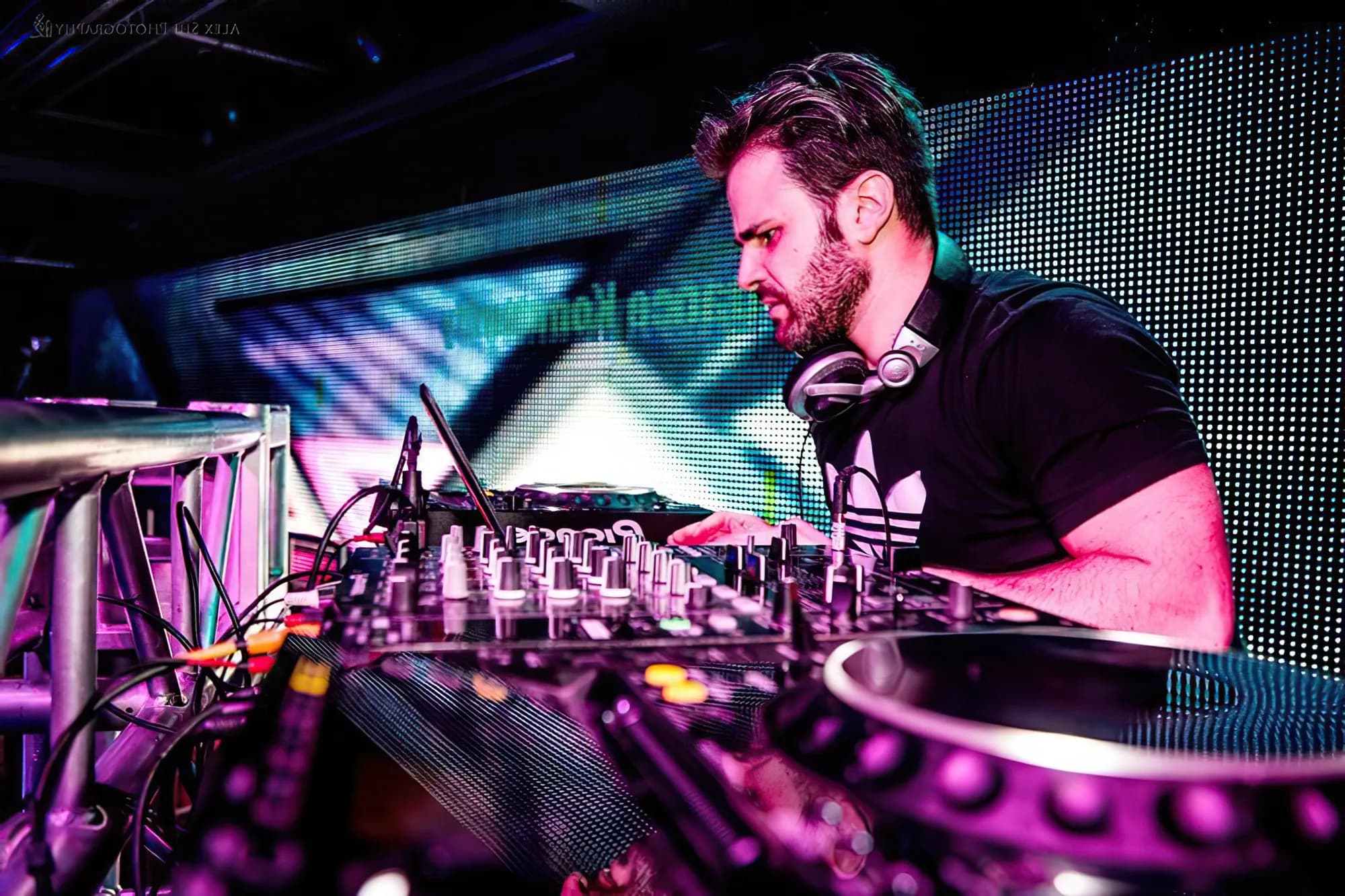 Gabriel mixing at the DJ booth under teal and blue production lighting