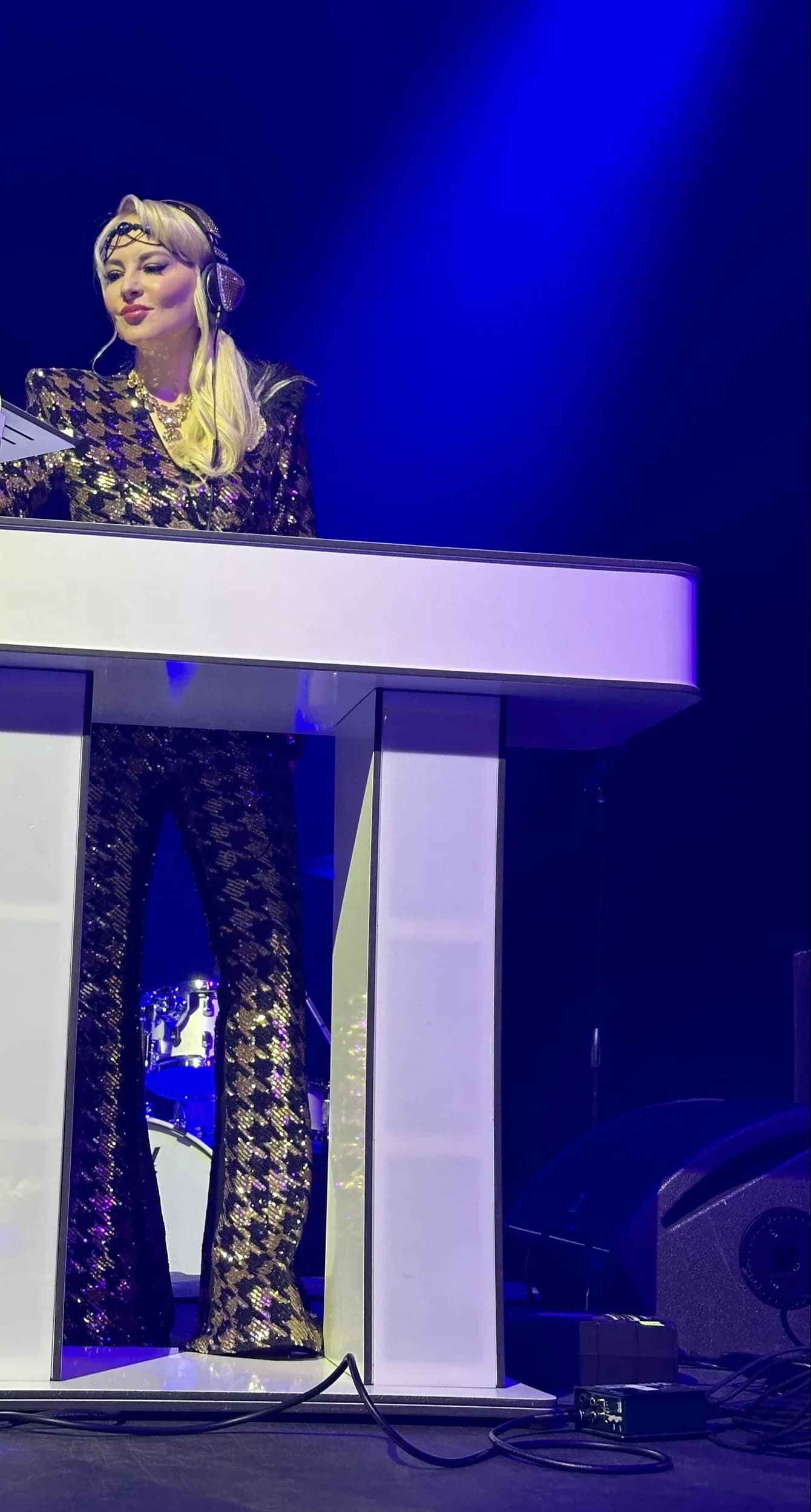 DJ Kristaval at her custom branded DJ booth in a gold houndstooth ensemble at a private NYC event