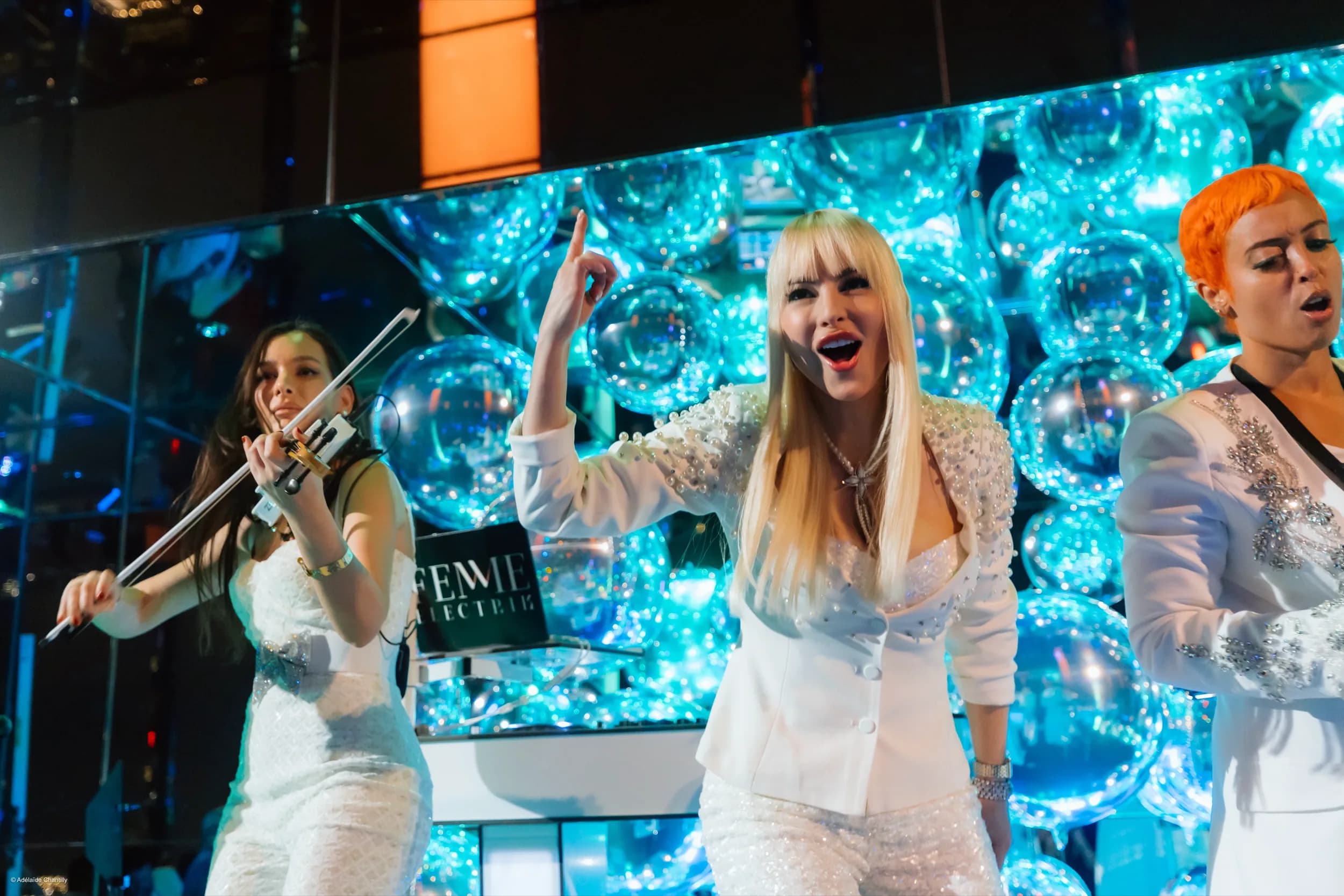 DJ Kristaval fronting her all-female live band on a luminous bubble-wall stage in NYC