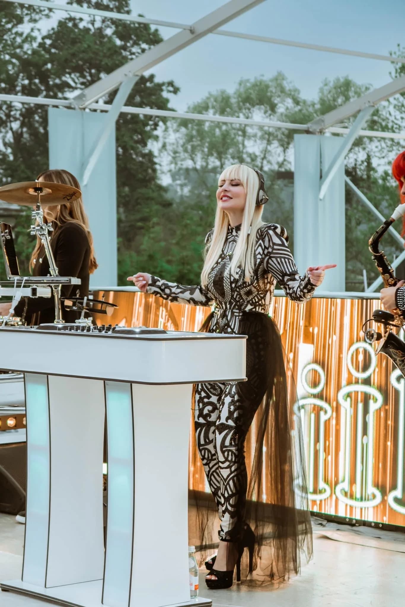 DJ Kristaval performing an open-air set under a tented venue with warm neon staging