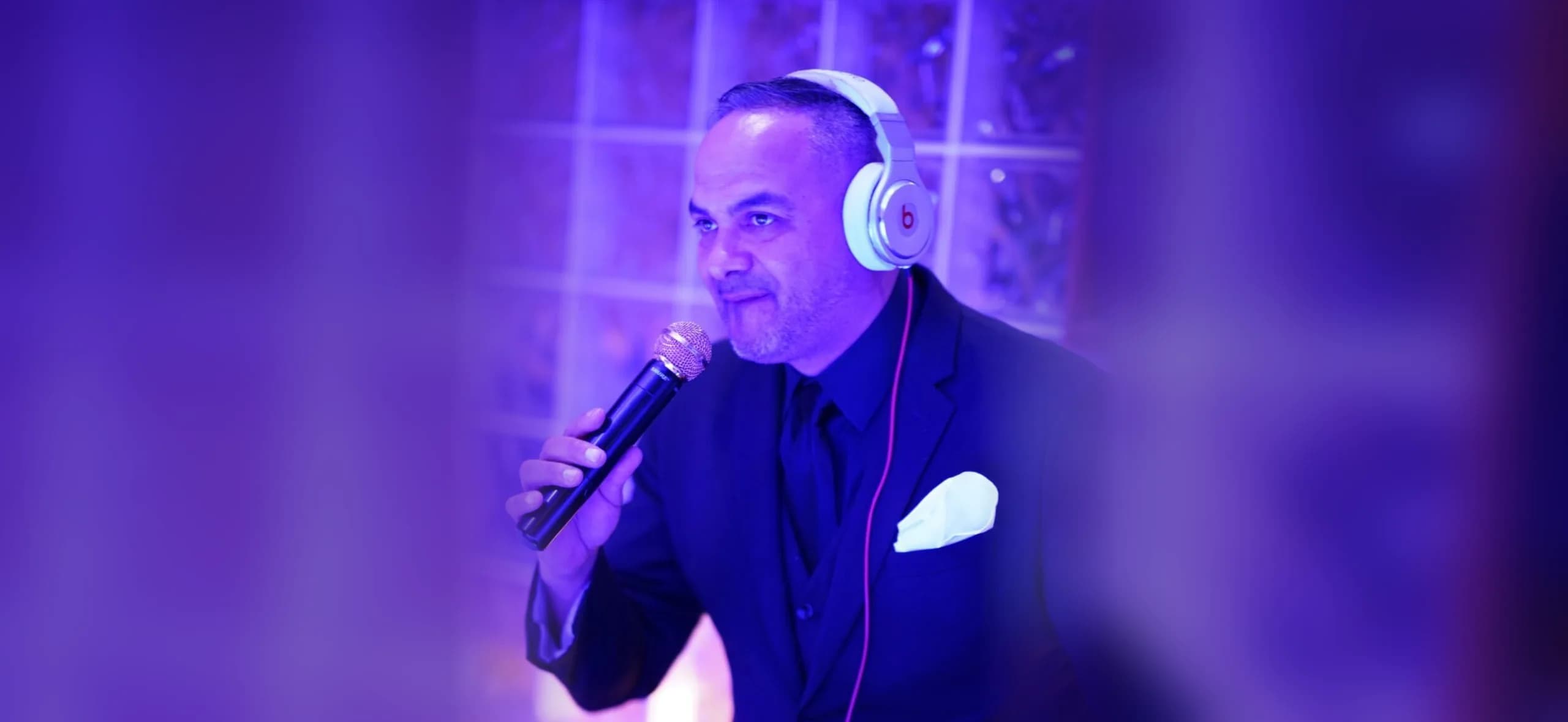 Omar on the microphone behind the decks, used as a dimmed atmospheric backdrop