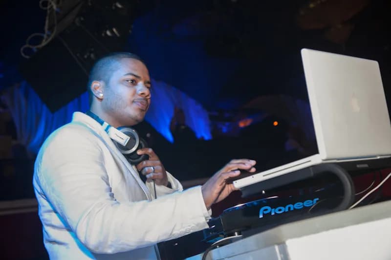 DJ Neza at the decks bathed in atmospheric blue event lighting