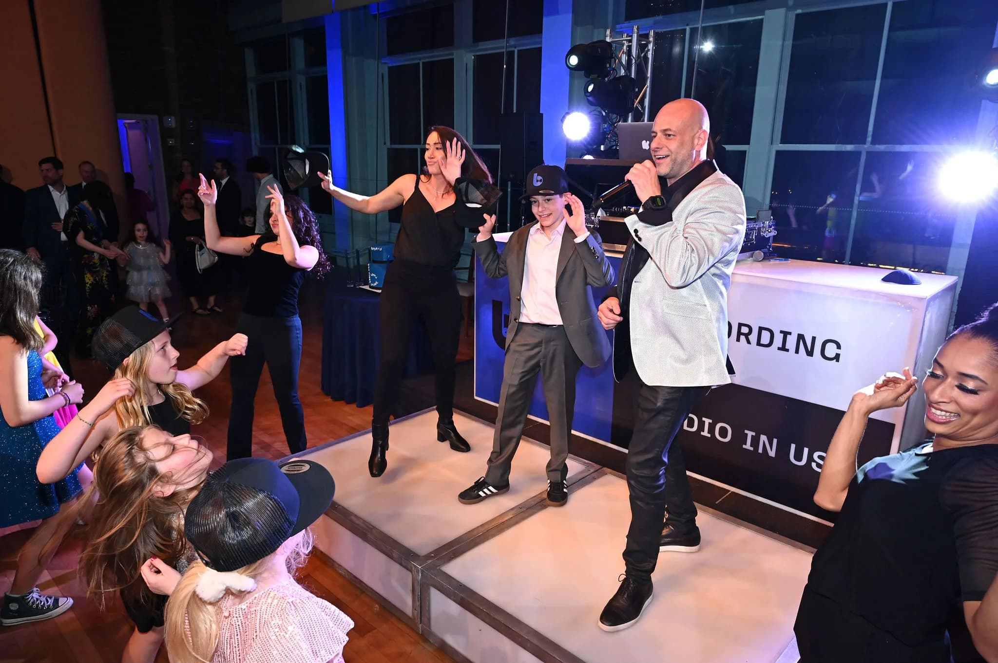 MC Shiran Nicholson on stage with dancers and a packed floor at a Bar Mitzvah production event