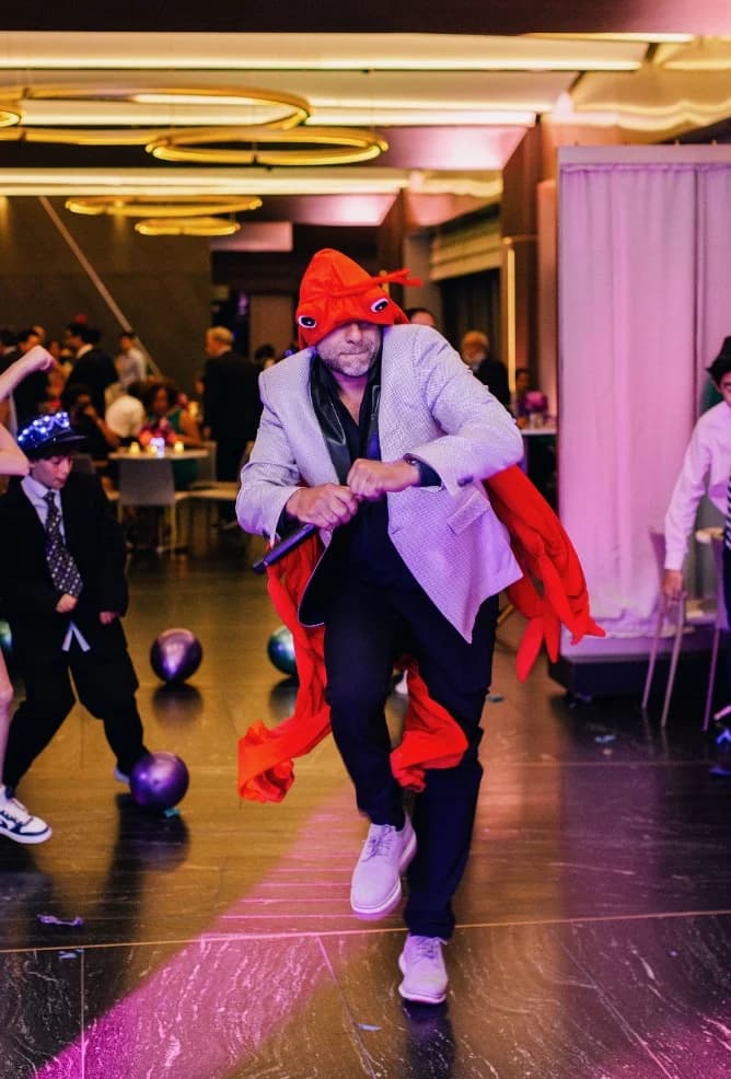 MC Shiran Nicholson in a playful goldfish costume energizing the dance floor at a New York bar mitzvah