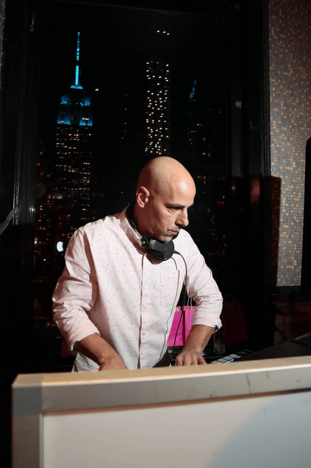 DJ Tommy performing at the decks against a dramatic NYC nighttime skyline at a private event