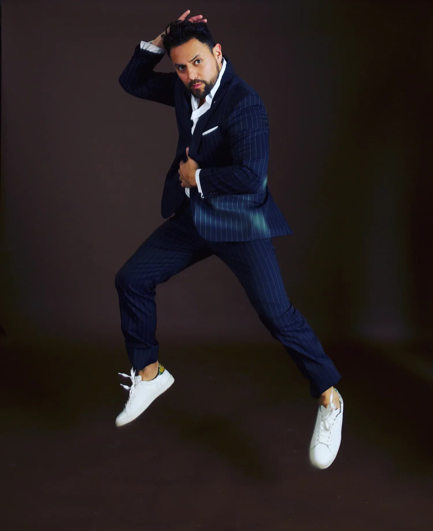 MC Nelson in a pinstripe suit jumping mid-air in a dramatic portrait shot