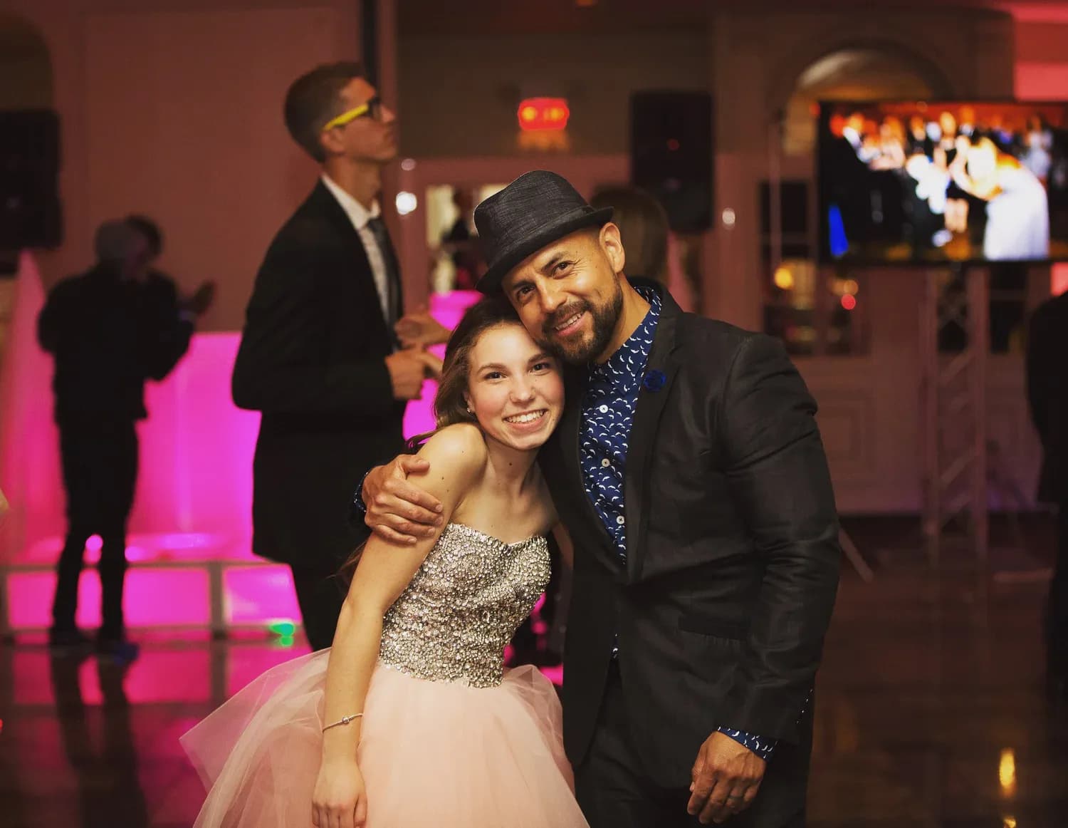 MC Nelson with the honoree at a sweet 16 celebration, warm event lighting