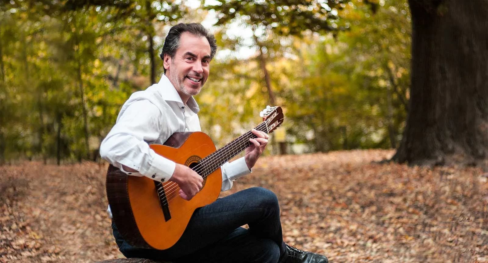 Tomas, Latin guitarist for weddings, cocktail hours, and private events in NYC and CT, posing outdoors with his classical guitar