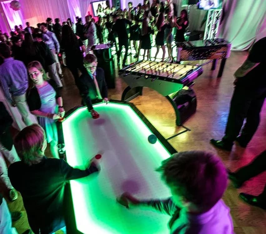 Oversized 6-player LED air hockey table at a bar mitzvah in NYC, six players competing three to a side on one glowing table