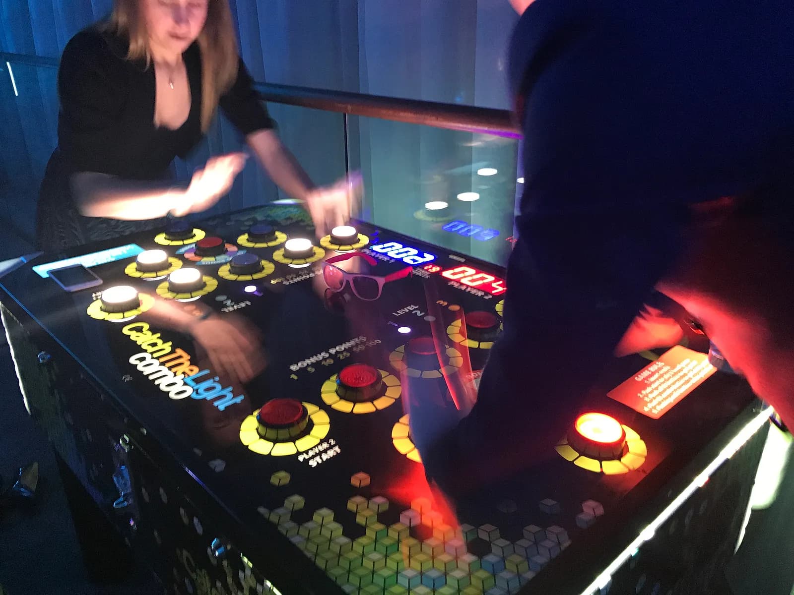 Two adults in formalwear competing head-to-head on the Catch the Light Combo reaction game at a corporate event in NYC