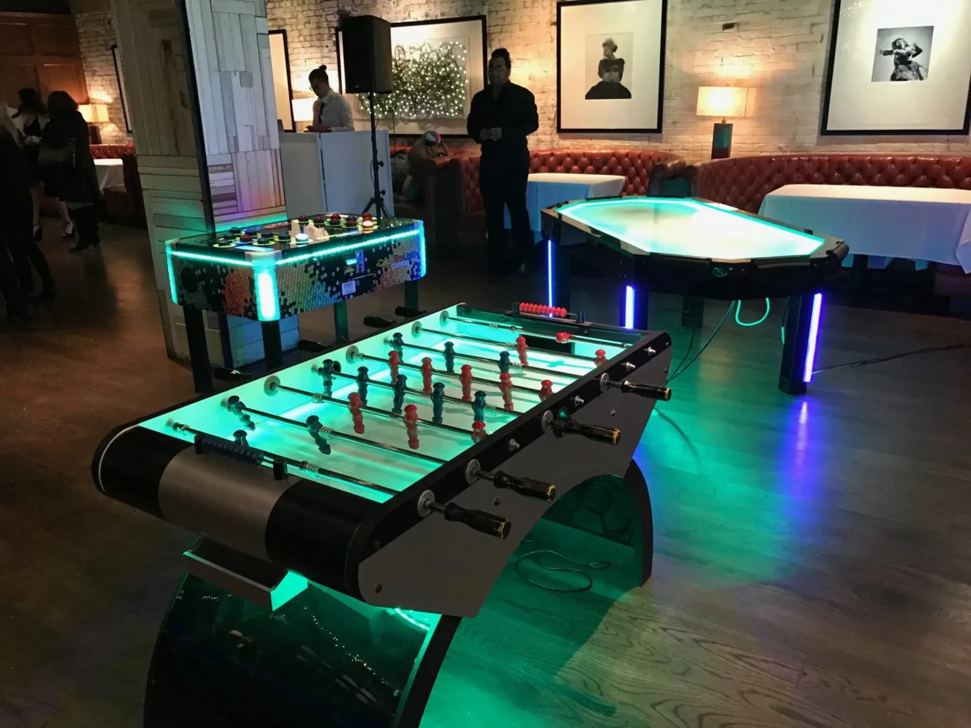 Guests playing LED foosball at an event in Connecticut, the glowing playfield and illuminated rods lighting up the dark party room