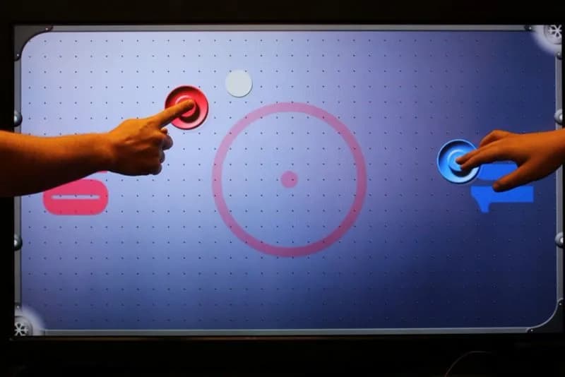 70-inch LED touch game table at a mitzvah party, guests playing multi-touch interactive games on the glowing white surface