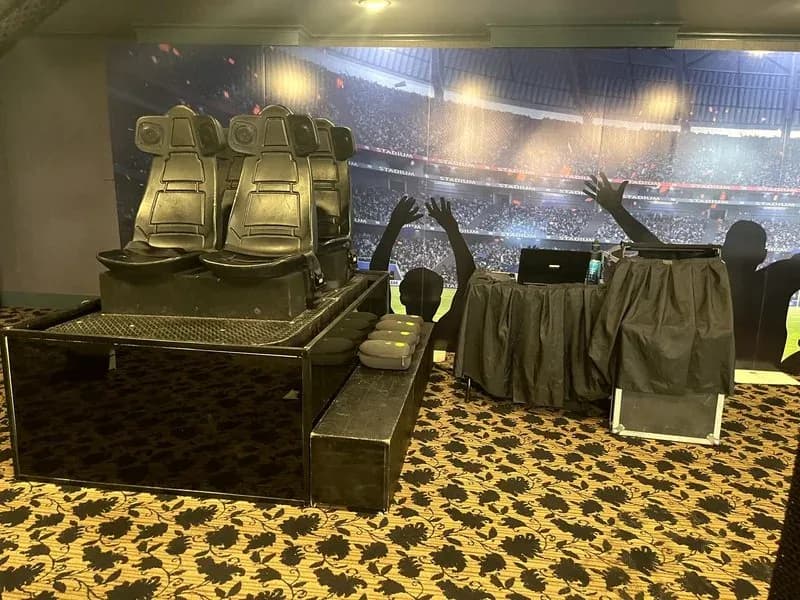 VR coaster 4-seat motion simulator ride at an event, an enclosed virtual reality roller coaster with motion seating and a stadium backdrop