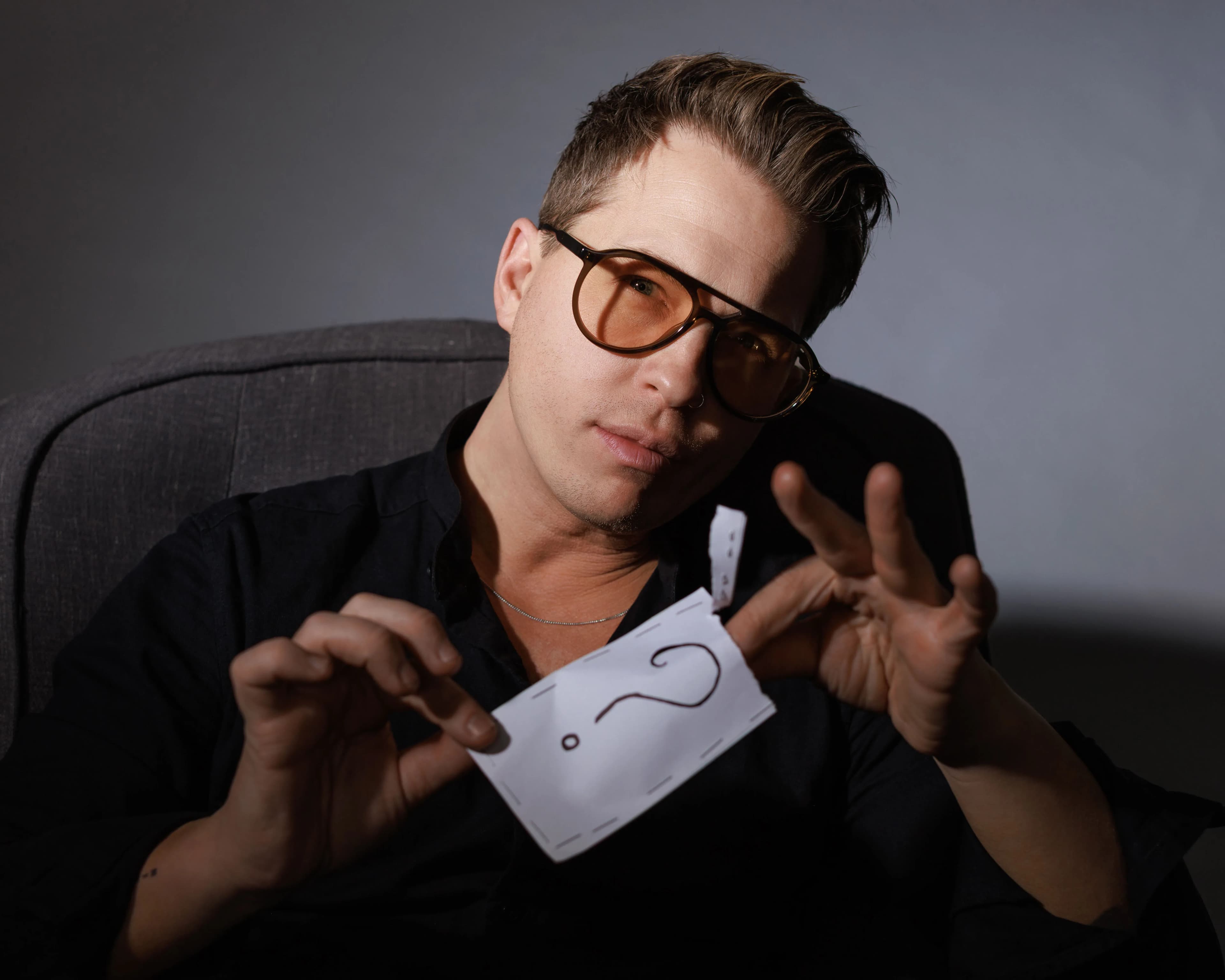 Kevin, the Modern Mentalist, in tinted glasses framing a question mark card between his hands during a mind-reading routine