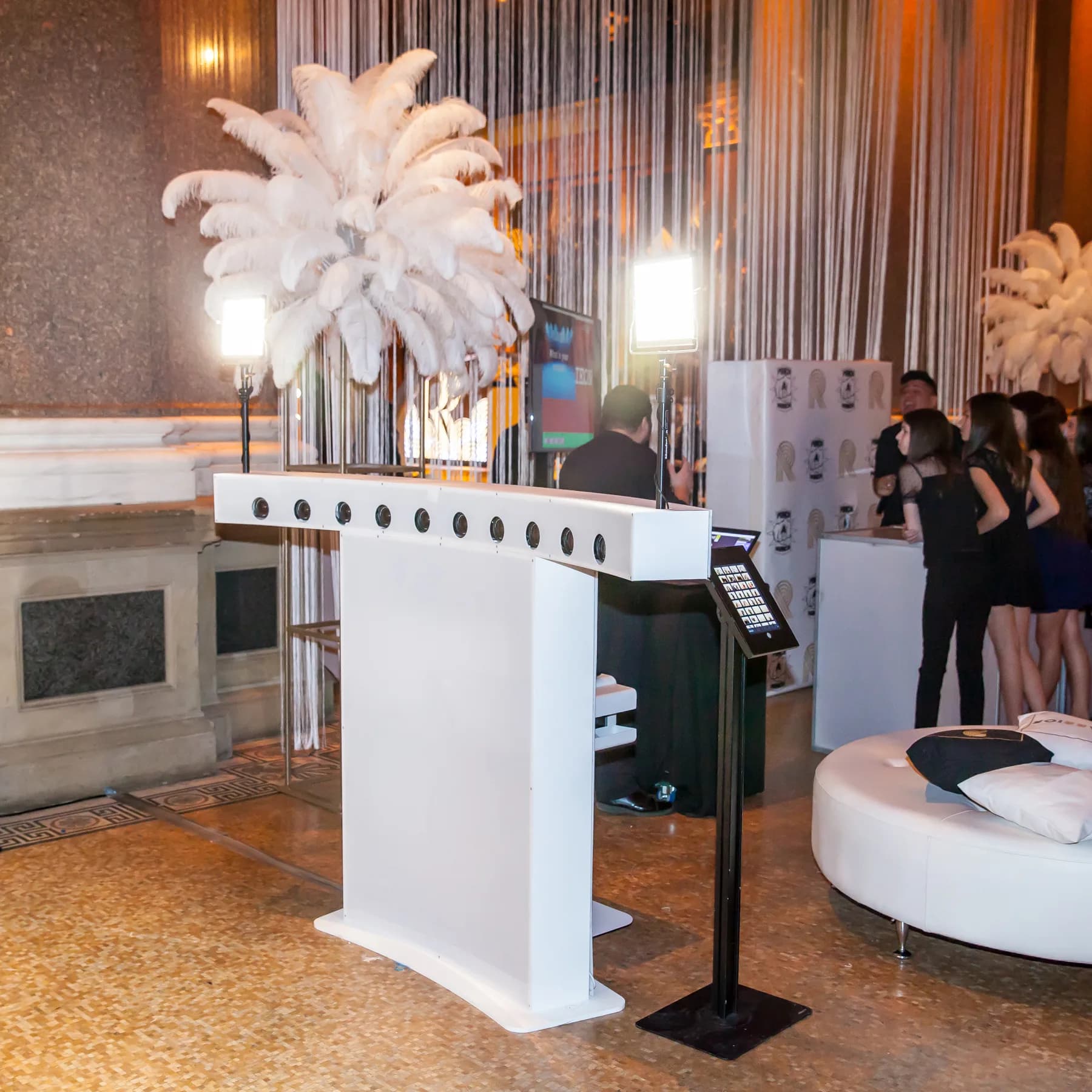 Camera array setup at a luxury venue with feather centerpieces and guests preparing for the activation