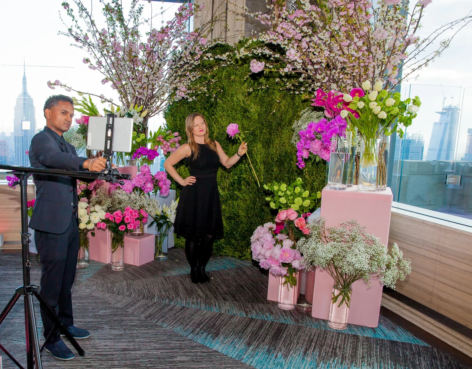 Attendant operating the sliding GIF rail while a guest poses with a flower at a New York City event