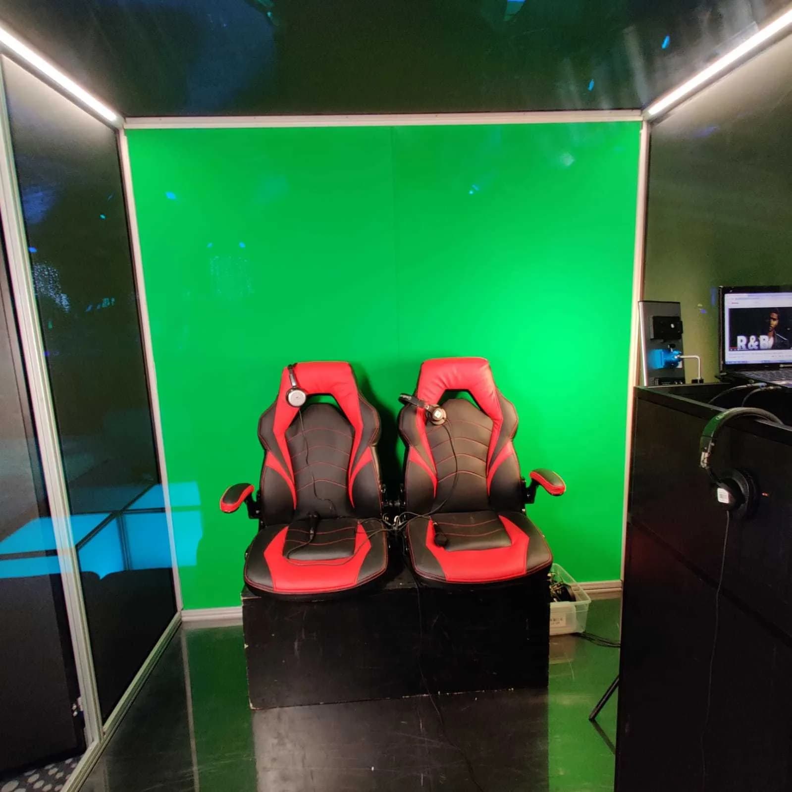 Clean interior shot of red and black racing seats against a bright green screen inside a car singing booth