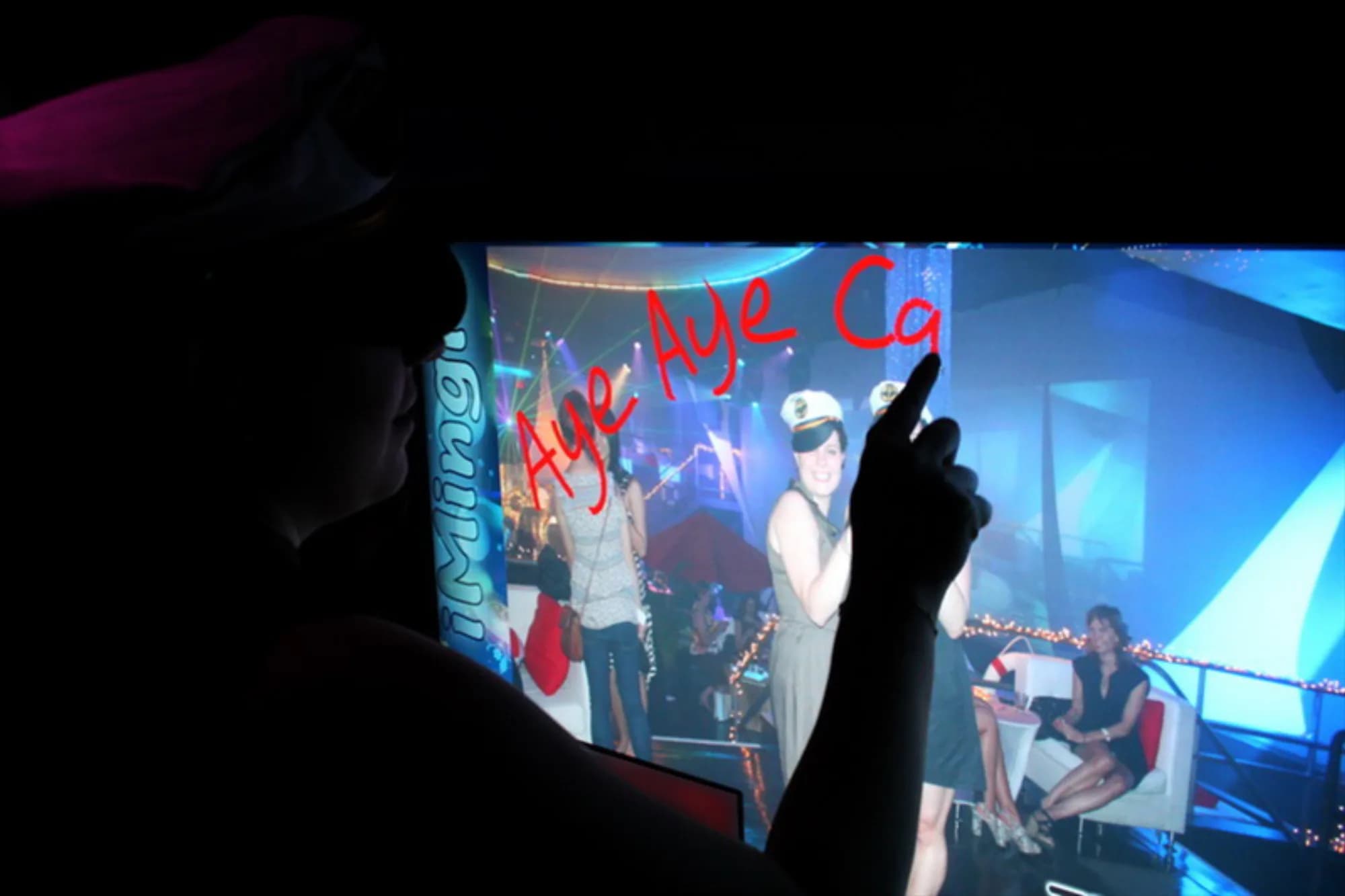Guest drawing on a digital graffiti kiosk screen showing a live event photo with virtual spray paint effects