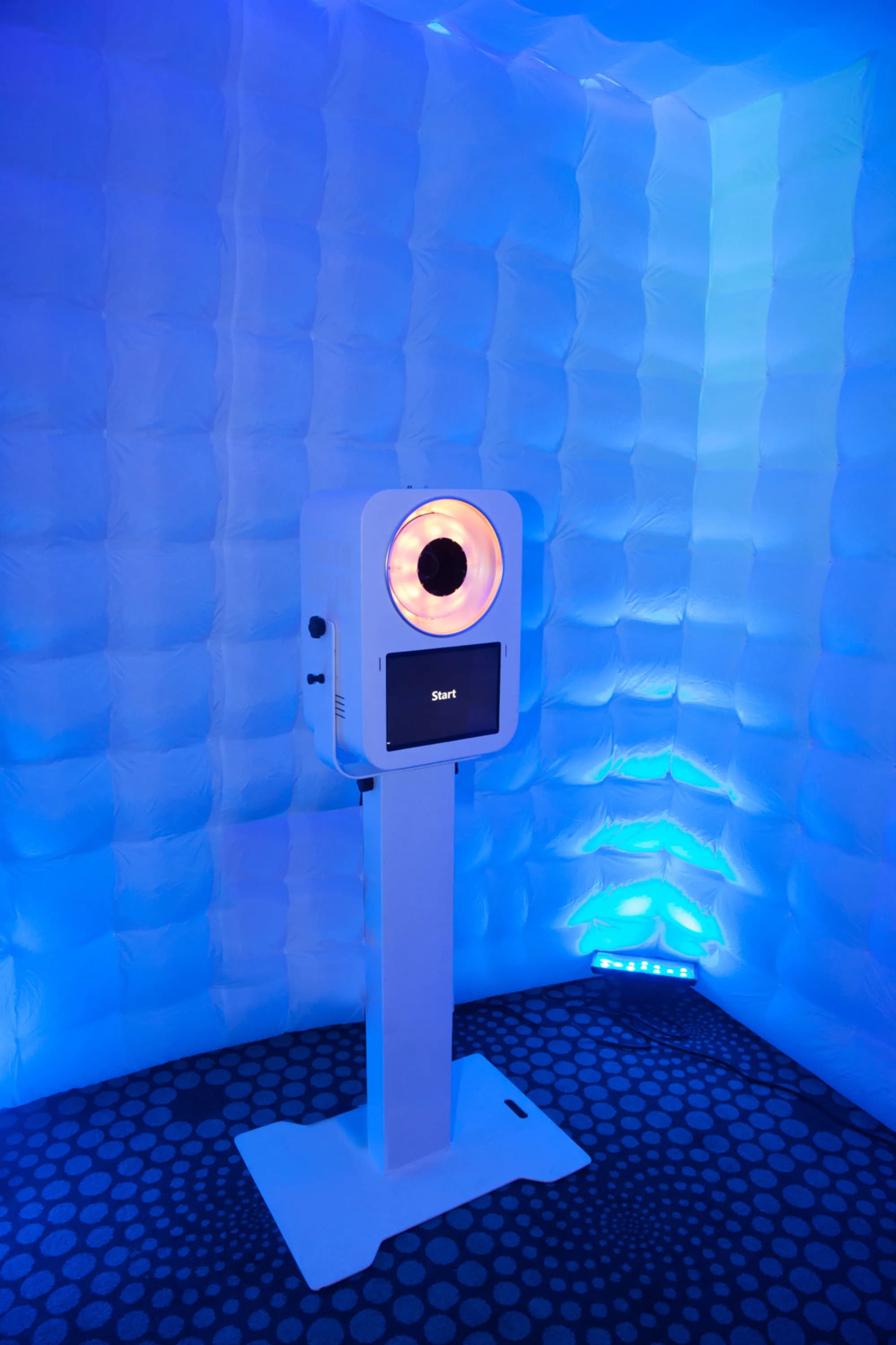 Interior of inflatable photo booth cube with open-air kiosk setup and LED blue ambient lighting