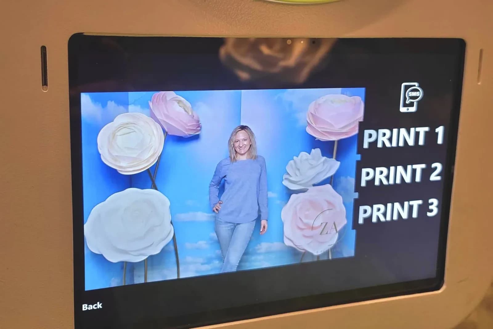 Guest previewing her photo on the touch-screen inside the flower garden with print and text-delivery options shown