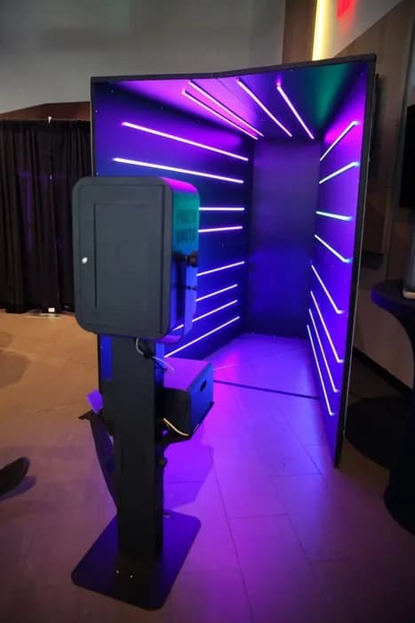 Open-air glam photo booth with purple and teal LED backdrop at a corporate event venue