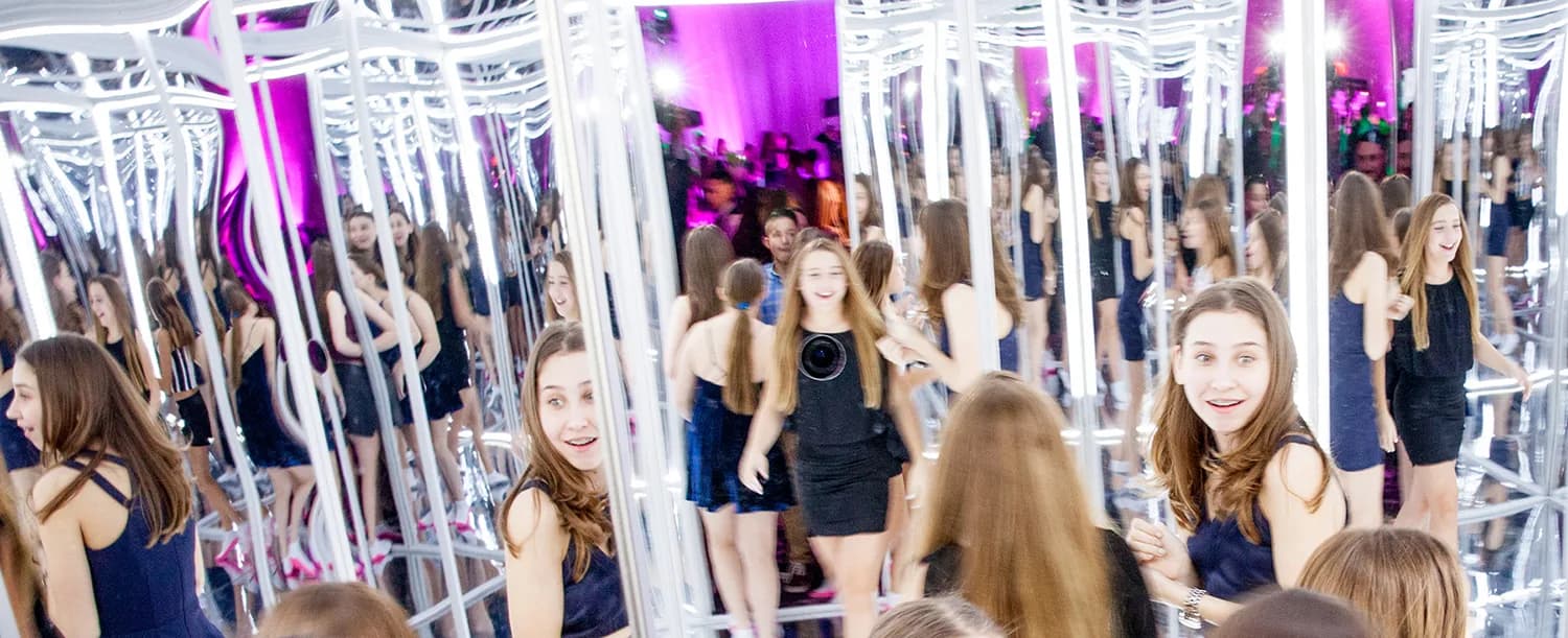 Wide shot of guests enjoying the infinite mirror room at a large mitzvah event with purple uplighting