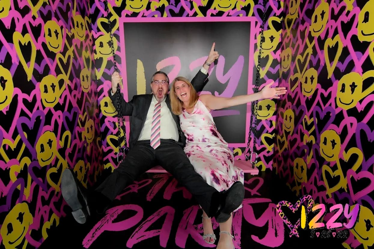 Guests laughing and posing on the photo swing inside a custom graffiti-themed immersive room at a sweet 16 party