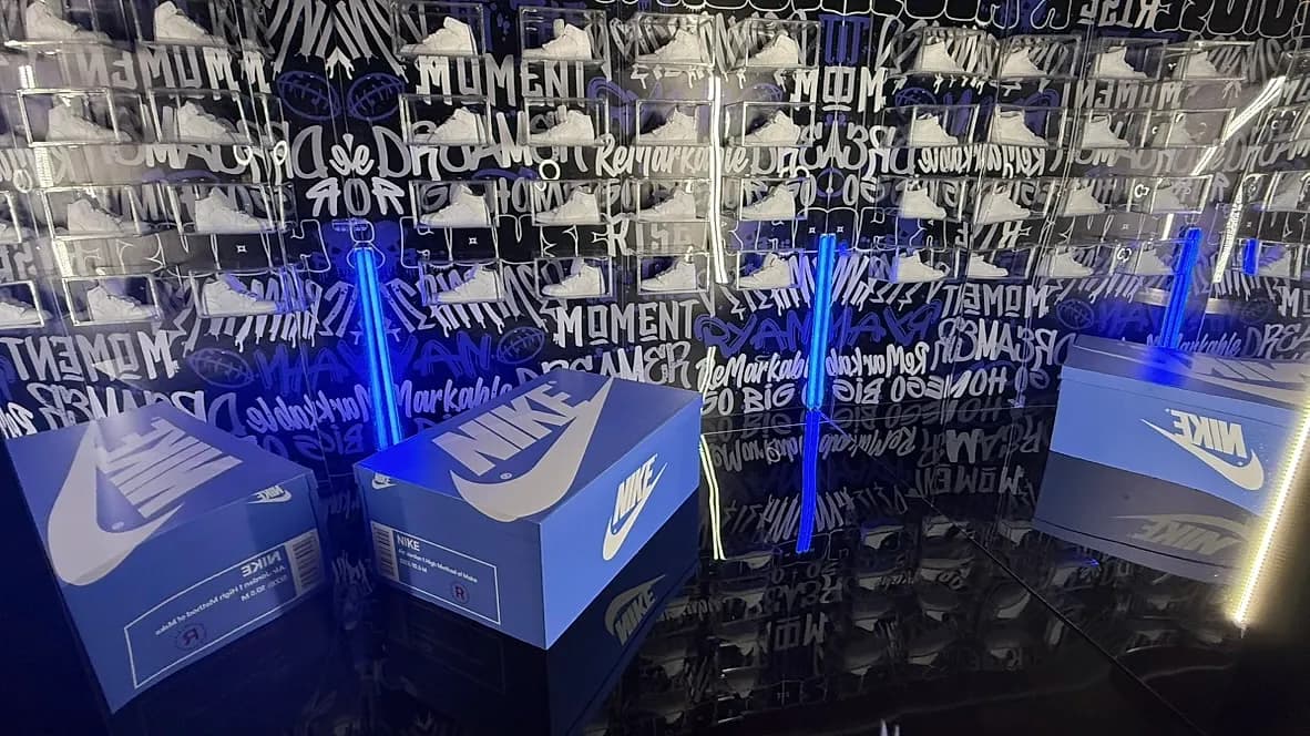 Custom immersive sneaker-box wall with illuminated shoe-box displays at a branded corporate activation produced by Nicholson Events