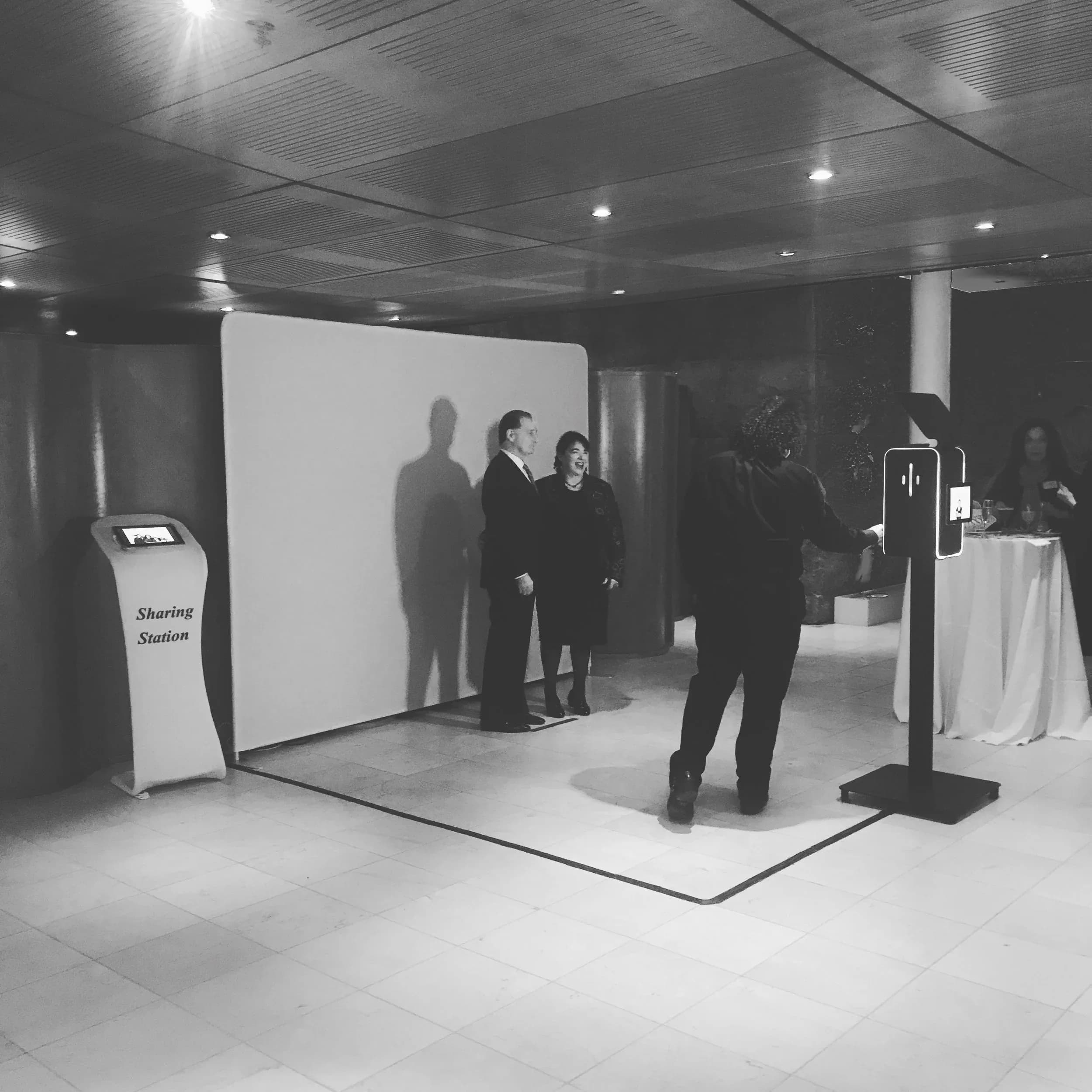 Black and white open-air photo booth at a corporate event showing the professional setup and camera