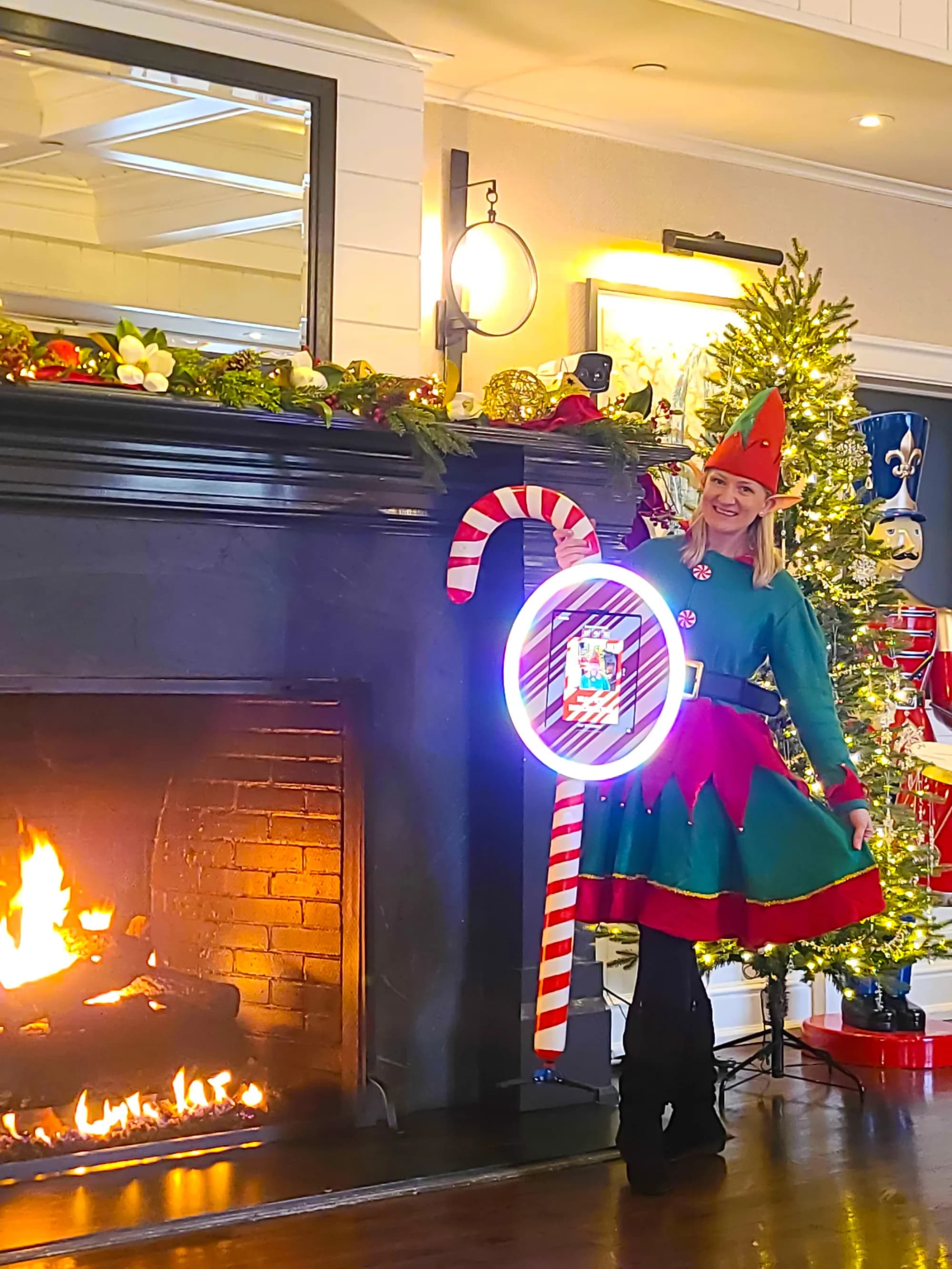 Holiday elf roaming photo attendant beside a fireplace at a corporate holiday party
