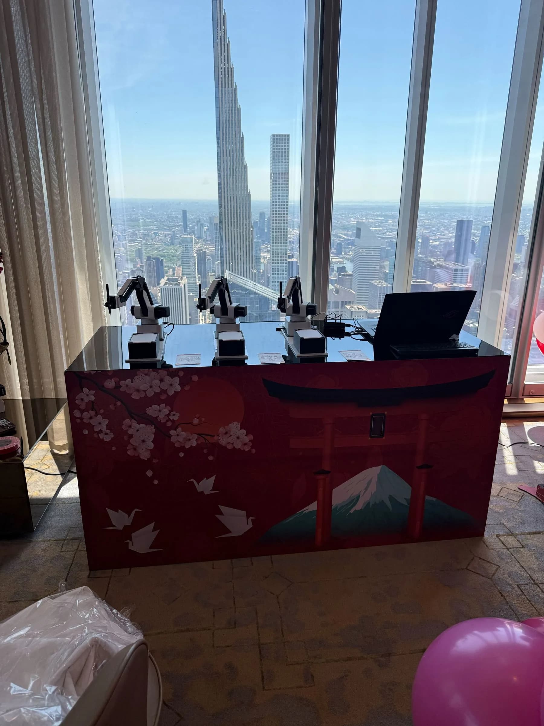 Multiple SketchBot robotic arms ready to draw at a high-rise event with NYC skyline view