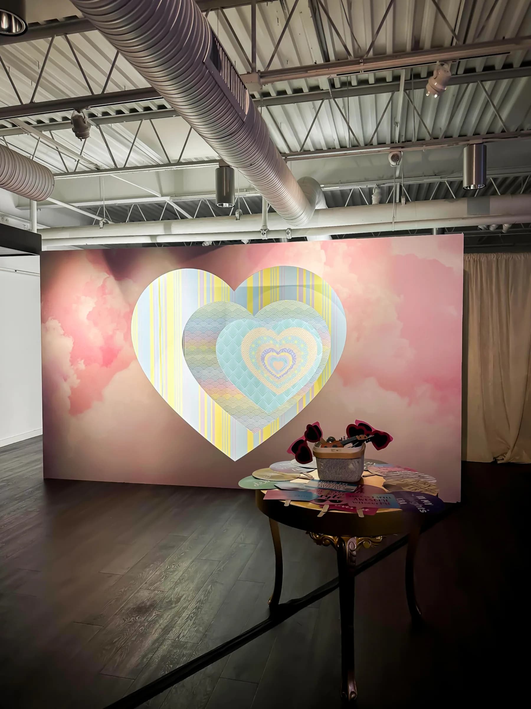 Endless hearts wall activation with pastel cloud mural backdrop and layered heart frame structure