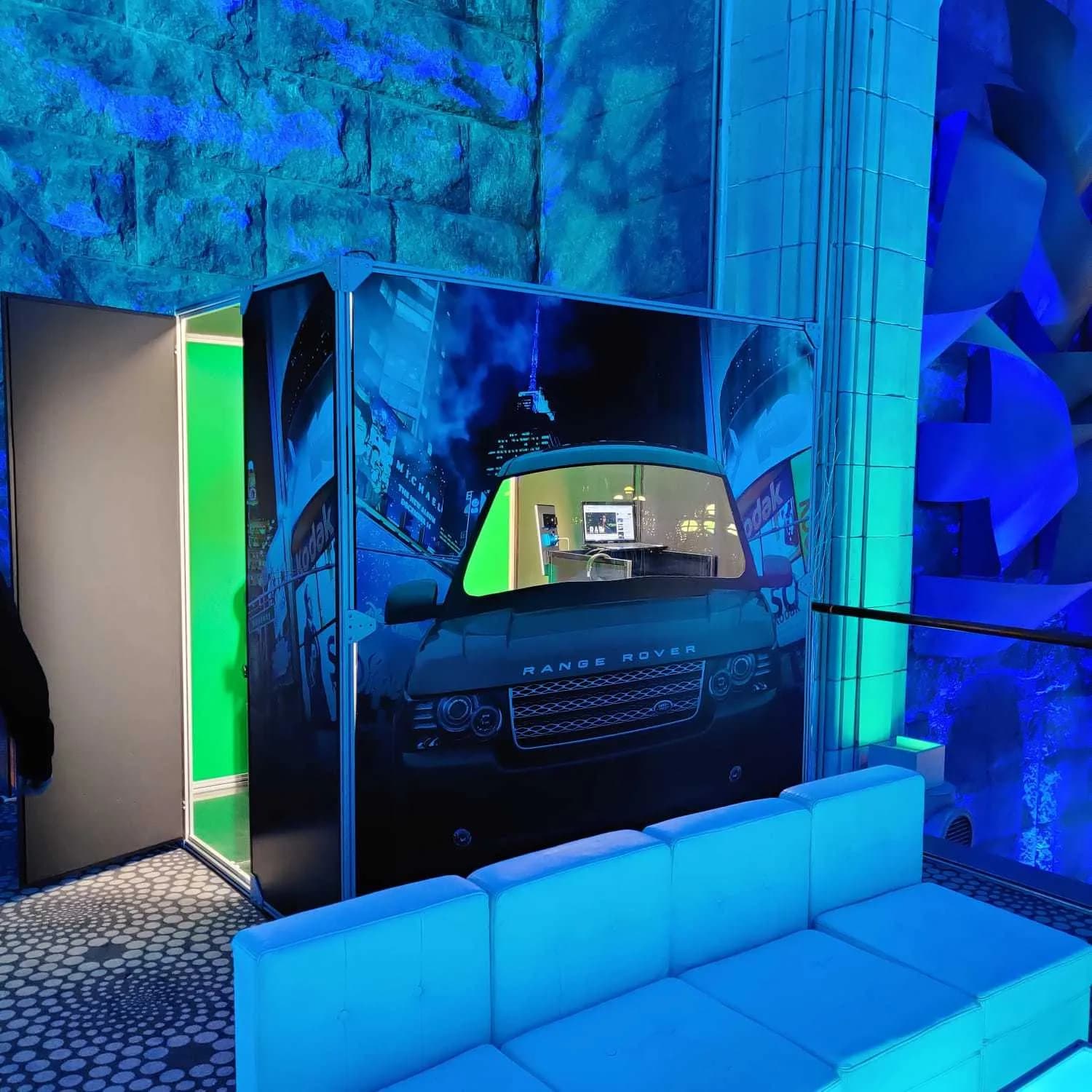 Enclosed car booth with vehicle facade wrap at a Nicholson Events celebration under blue event lighting