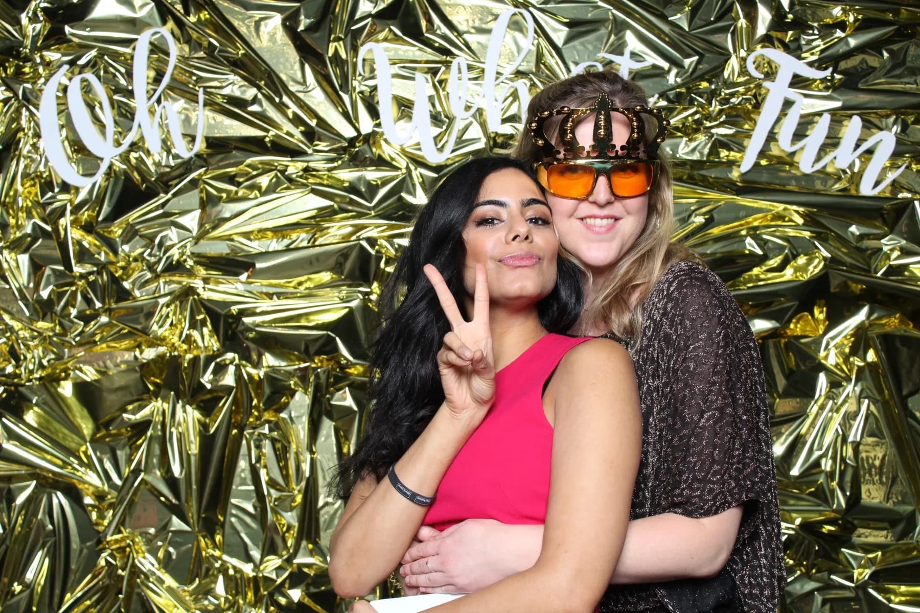 Couple posing in front of a gold crinkle foil backdrop at a Nicholson Events themed photo station
