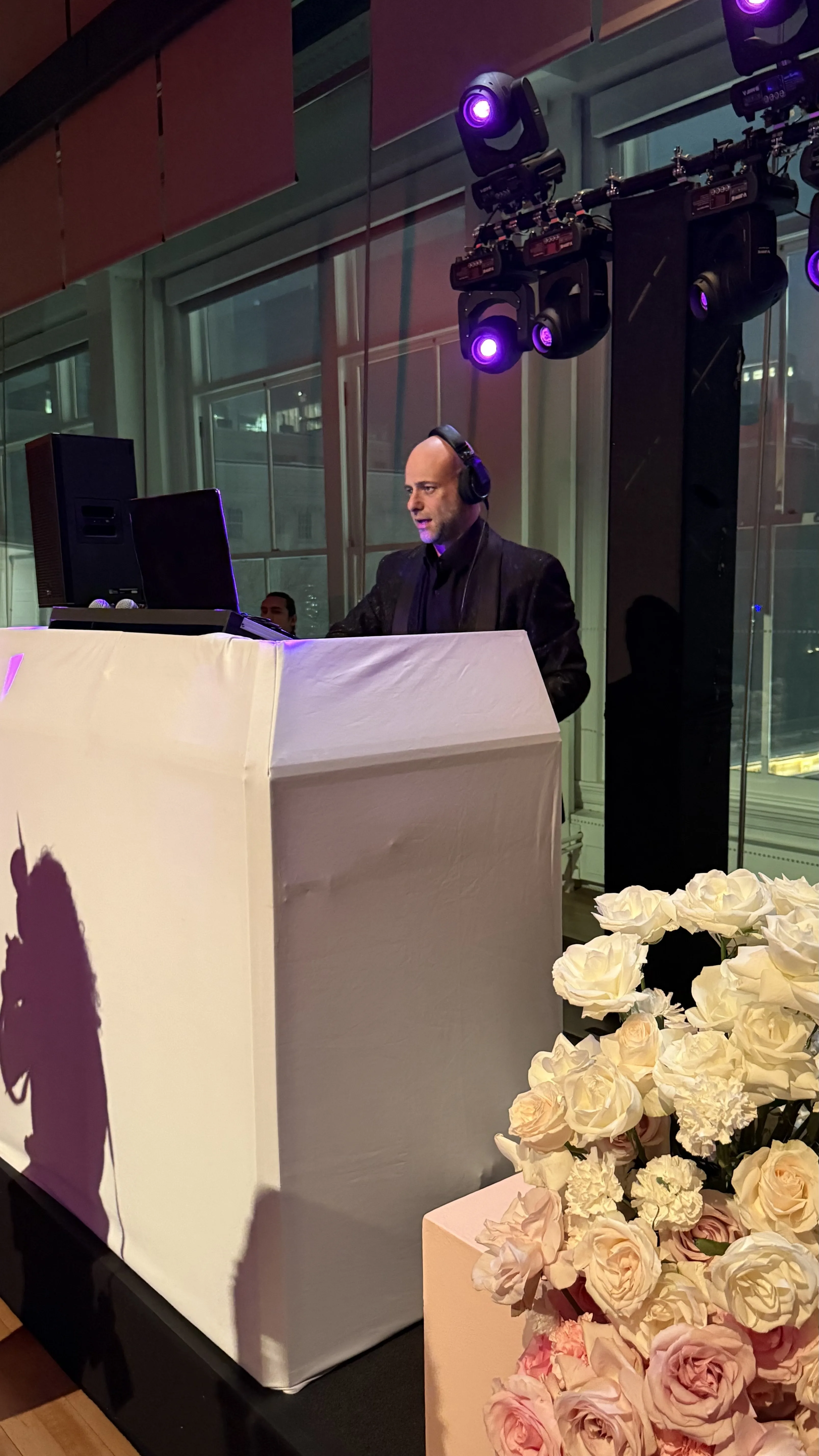 Wedding DJ planning the reception flow at an upscale New York venue with white roses for Nicholson Events